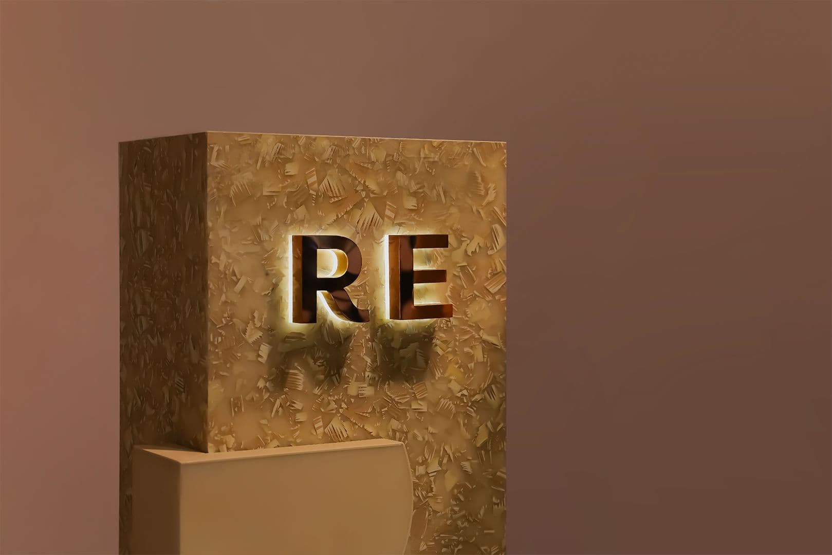 Panel decorativo con letras RE iluminadas y un elemento de pedestal, parte de un escaparate completo realizado por PRETENDE.