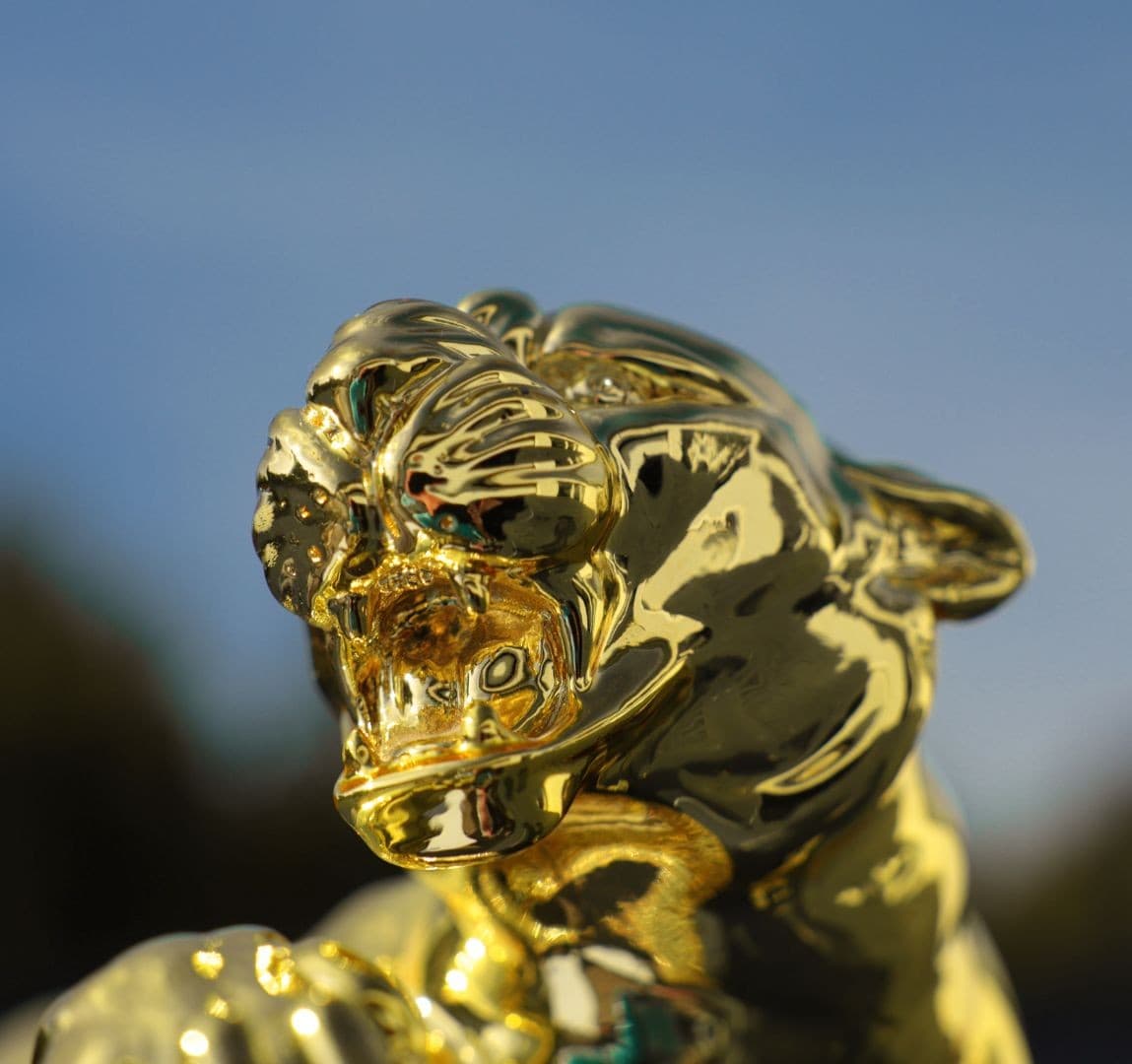 Goldene Puma-Skulptur aus Edelstahl Der Kopf des Pumas ist Teil einer monumentalen Skulptur aus Edelstahl mit einer polierten, spiegelglatten Oberfläche und einer goldenen Veredelung. Der hohe Glanz betont die Konturen von Schnauze und Ohren sowie die Muskelspannung und spiegelt gleichzeitig den Himmel und die Umgebung der Installation wider. Die so gestaltete Oberfläche verändert je nach Lichteinfall die Wahrnehmung der Form und setzt einen dekorativen, reflektierenden Akzent im öffentlichen Raum.